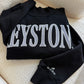 Black sweatshirt with 'KEYSTONE' printed on it, lying on a textured surface.