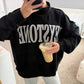 Person wearing a black sweatshirt with 'KEYSTONE' text, holding a drink.