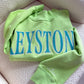 Green sweatshirt with 'KEYSTONE' printed in blue on a beige surface