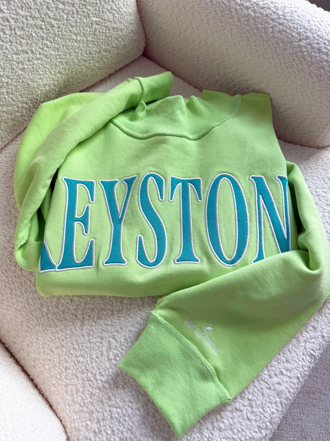 Green sweatshirt with 'KEYSTONE' printed in blue on a beige surface