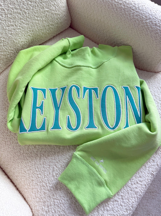 Green sweatshirt with 'KEYSTONE' printed in blue on a beige surface