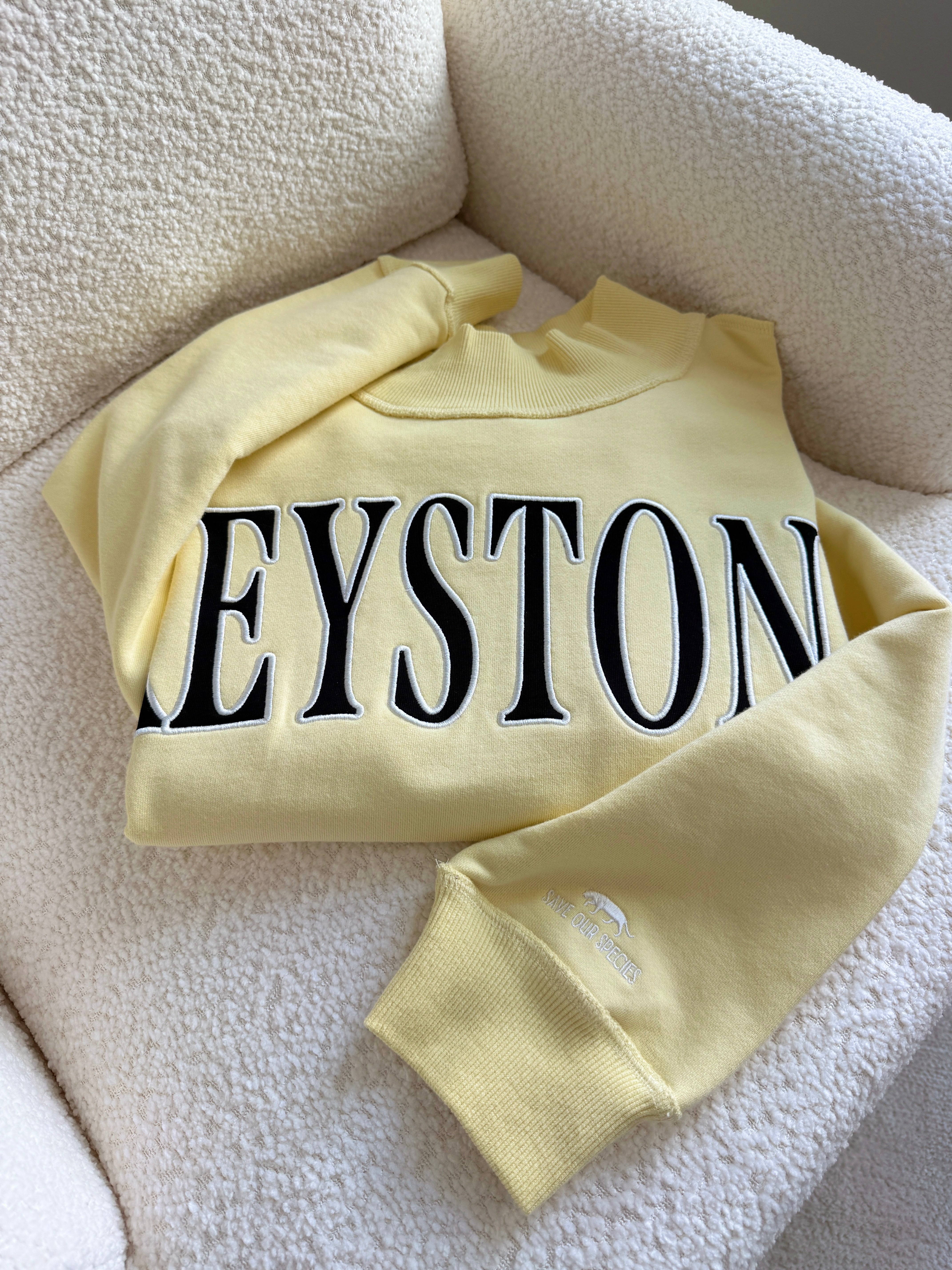 Yellow sweatshirt with 'KEYSTONE' text on a white surface