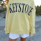 Person wearing a yellow sweatshirt with 'KEYSTONE' text on a beach.