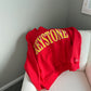 Red sweatshirt with yellow 'Keystone' text on a white couch against a gray wall.